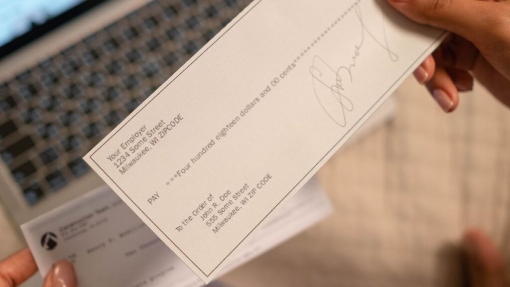 Customer holding a cheque while writing an application to bank manager