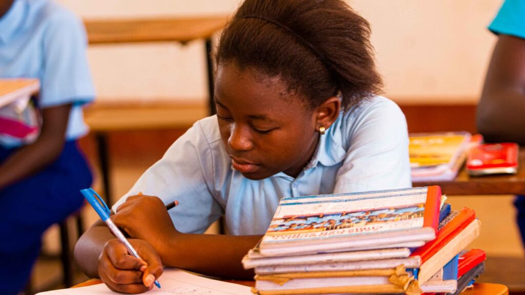 Student writing a leave application for school in a notebook